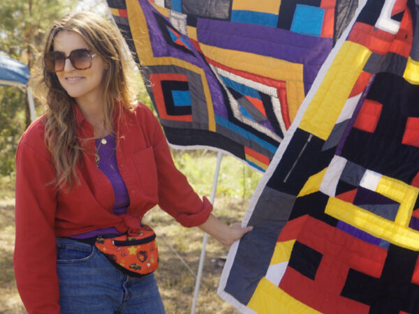 Katherine Jentleson, curator of folk and self-taught art at the High Museum of Art stands next to several colorful quilts hanging from clotheslines at the annual Airing of the Quilts Festival in Boykin, Alabama.